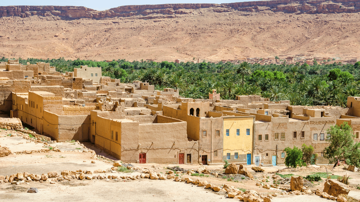 Sunlight bathes serene Ziz Valley Morocco, where towering cliffs embrace a lush oasis.